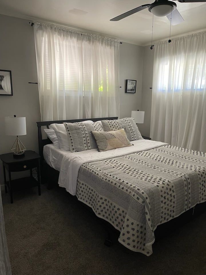 A bedroom with white curtains and a bed