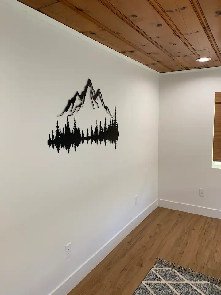 A room with wood floors and a wall that has a mountain scene on it.