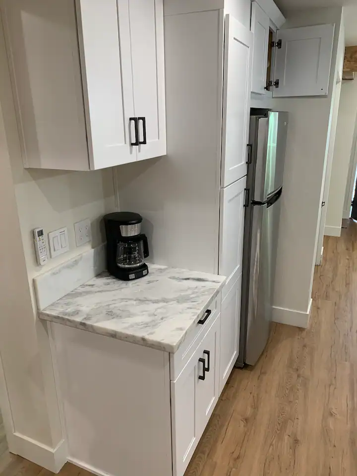 A kitchen with white cabinets and wood floors.