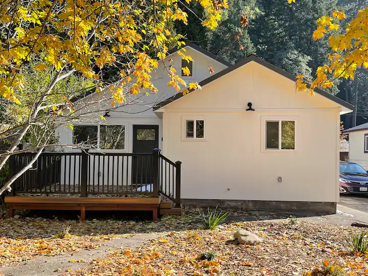 A white house with a wooden deck in front of it.