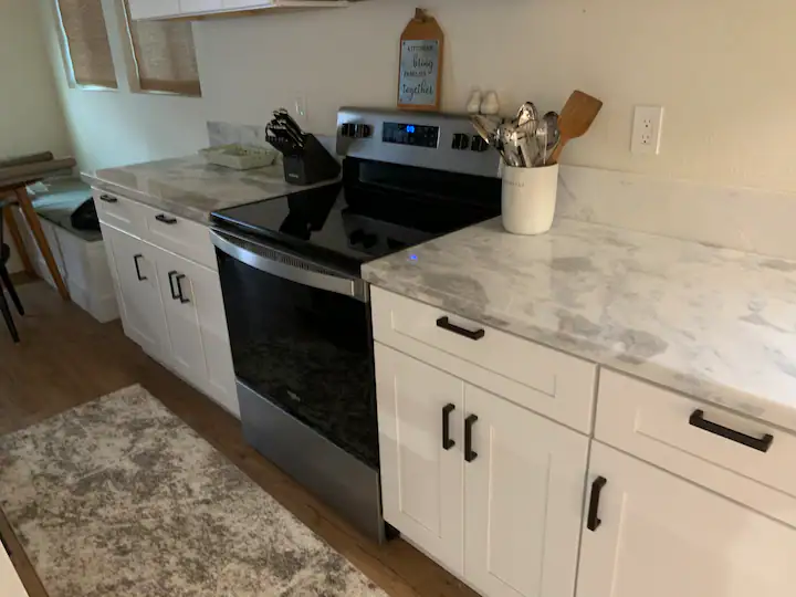 A kitchen with white cabinets and black appliances.