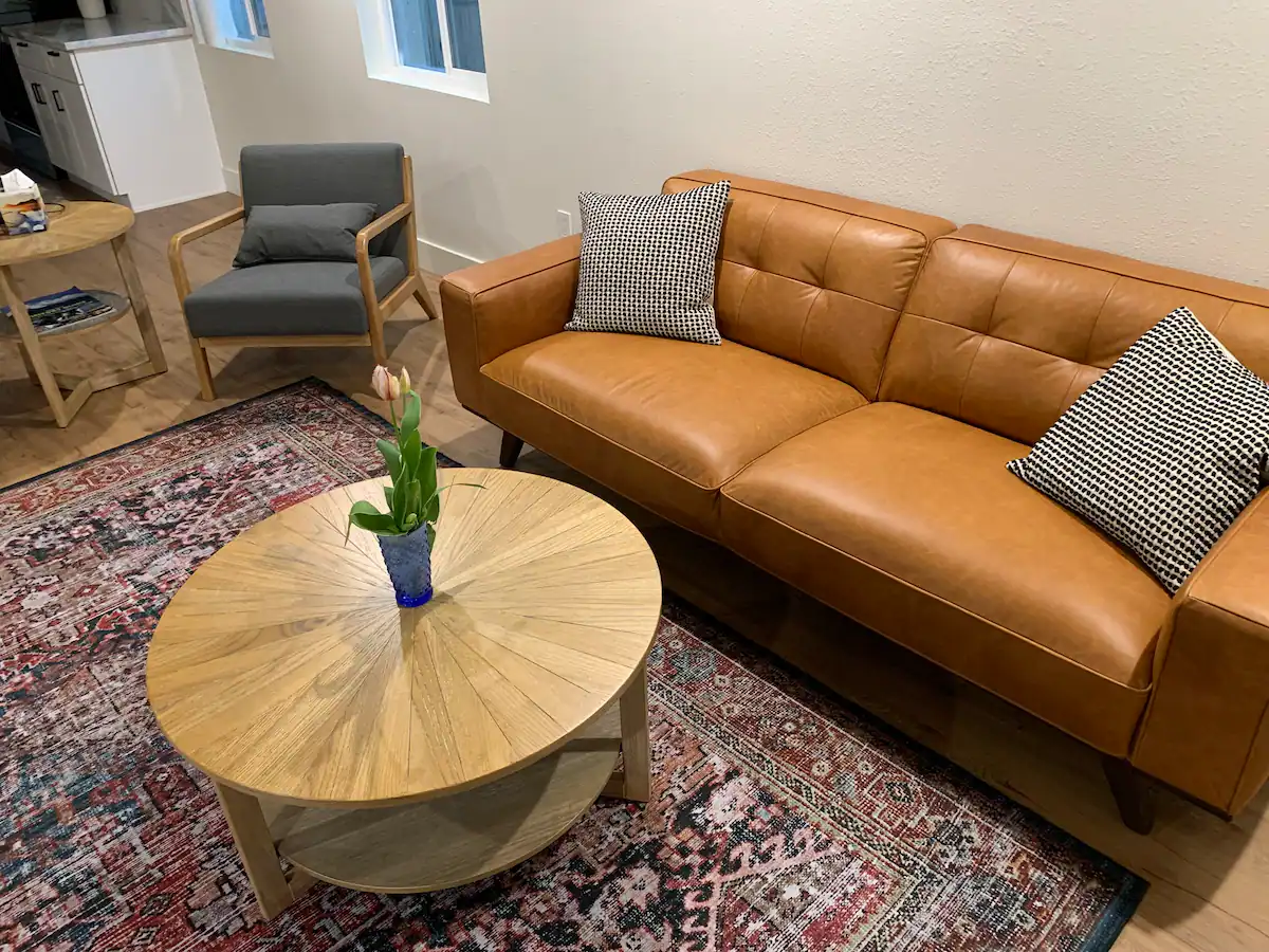 A living room with brown leather couch and wooden coffee table.