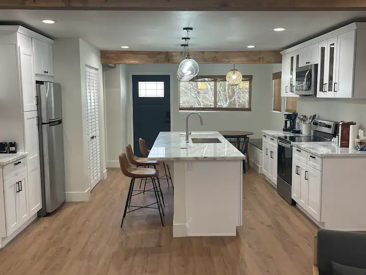 A kitchen with white cabinets and wood floors.