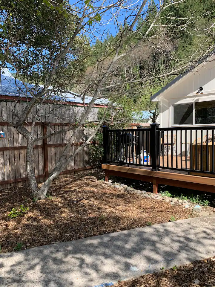 A house with a dog sitting on the back deck.