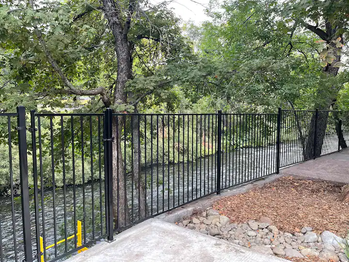 A fence that is made of metal and has trees in the background.